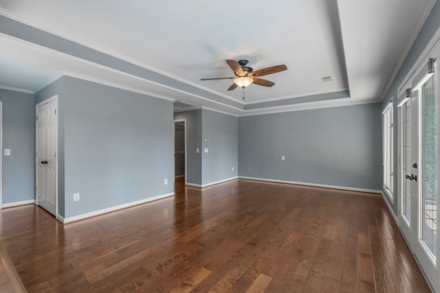 empty room with crown molding, ceiling fan, a raised ceiling, baseboards, and dark wood-style floors