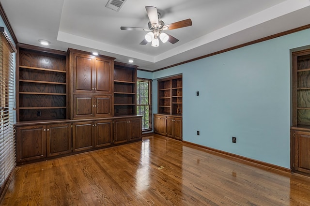 interior space with baseboards, a ceiling fan, wood finished floors, and visible vents