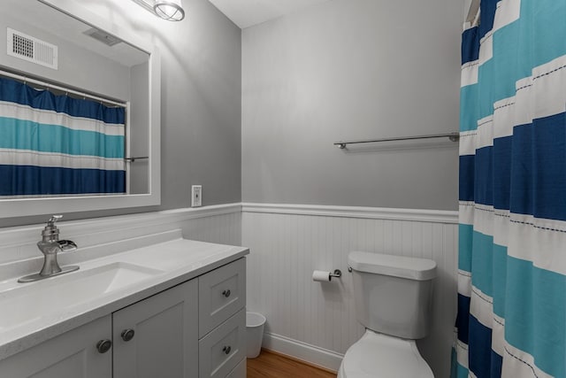 bathroom with visible vents, wood finished floors, a wainscoted wall, vanity, and toilet