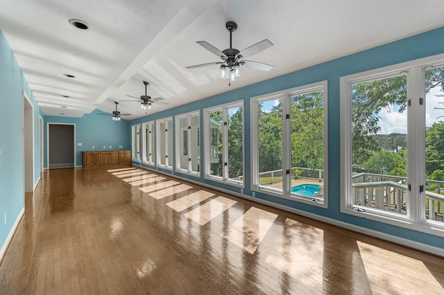 unfurnished sunroom with baseboards, lofted ceiling with beams, and wood finished floors