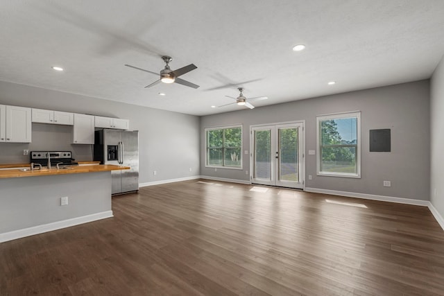 unfurnished living room with baseboards, a wealth of natural light, and dark wood-type flooring