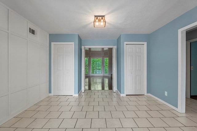 unfurnished bedroom with multiple closets, baseboards, and visible vents