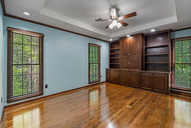 unfurnished room featuring plenty of natural light, a raised ceiling, and wood finished floors