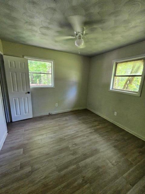 unfurnished room with ceiling fan and dark wood-type flooring