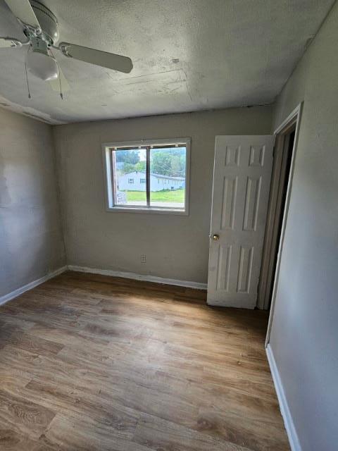 unfurnished room featuring ceiling fan, light hardwood / wood-style floors, and a textured ceiling