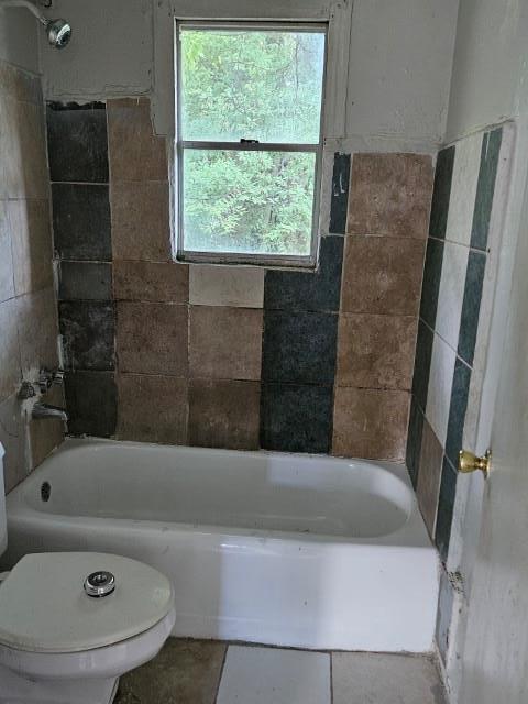 bathroom with tiled shower / bath combo and toilet