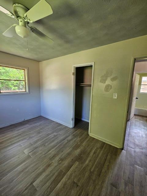 unfurnished bedroom with a closet, multiple windows, and dark hardwood / wood-style floors