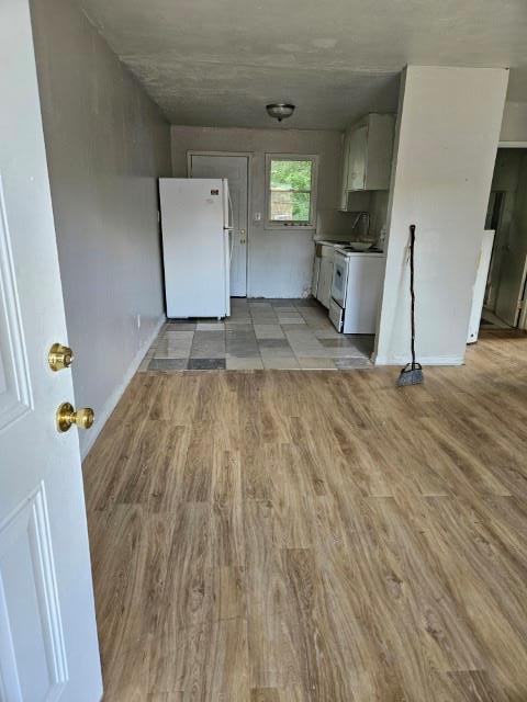 kitchen featuring white appliances, light hardwood / wood-style floors, and white cabinetry