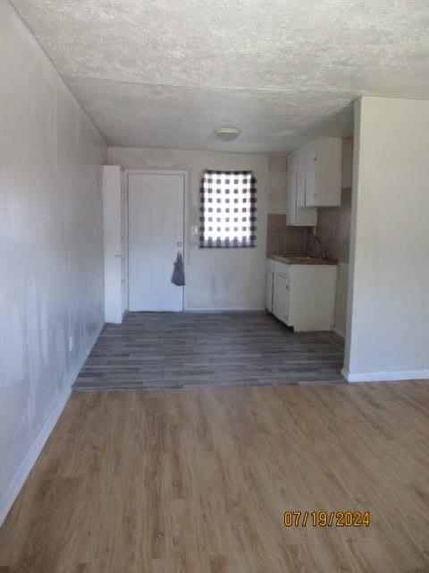 unfurnished living room with a textured ceiling, dark wood-type flooring, and sink