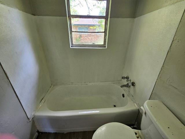 bathroom with a washtub and toilet