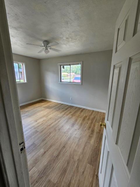 unfurnished room featuring a textured ceiling, light wood-type flooring, and ceiling fan