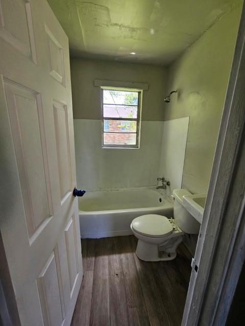 bathroom featuring hardwood / wood-style floors, toilet, and washtub / shower combination