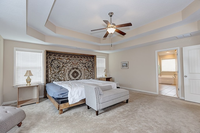 bedroom featuring a tray ceiling, multiple windows, carpet, and visible vents