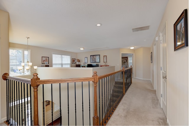 hallway with baseboards, visible vents, an upstairs landing, carpet floors, and a chandelier