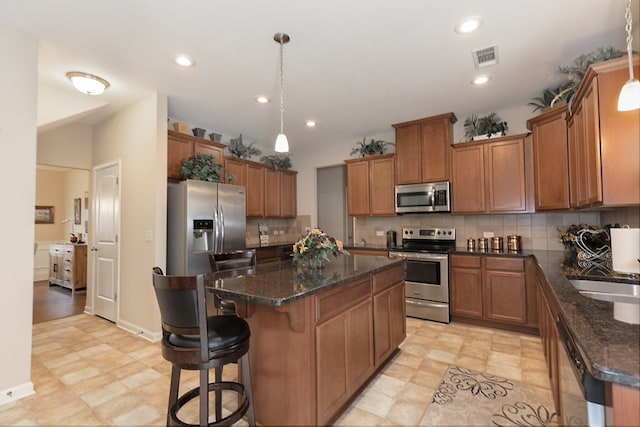 kitchen featuring appliances with stainless steel finishes, brown cabinetry, a kitchen island, and backsplash