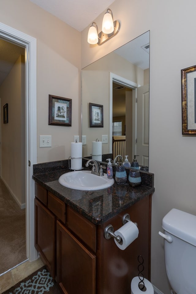 half bath with tile patterned flooring, vanity, and toilet