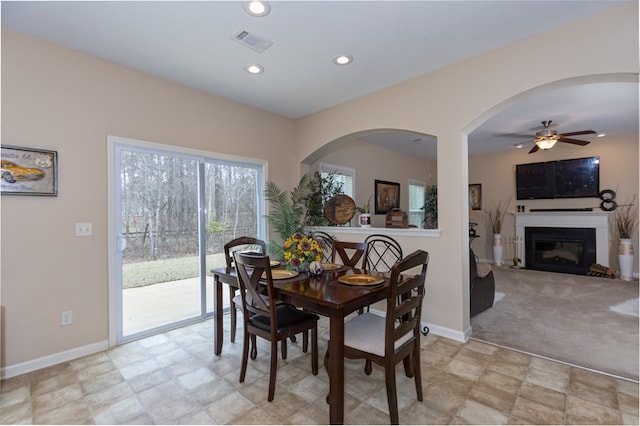 dining space featuring baseboards, visible vents, light colored carpet, a glass covered fireplace, and recessed lighting