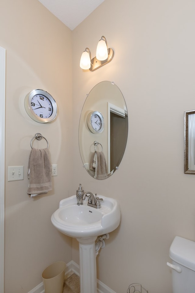 bathroom featuring baseboards, a sink, and toilet