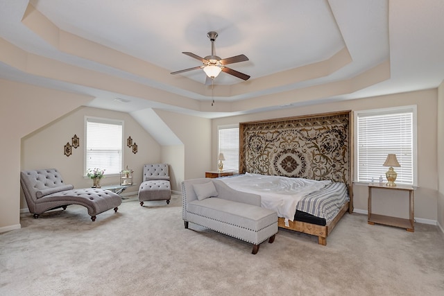 bedroom featuring light carpet, a tray ceiling, and multiple windows