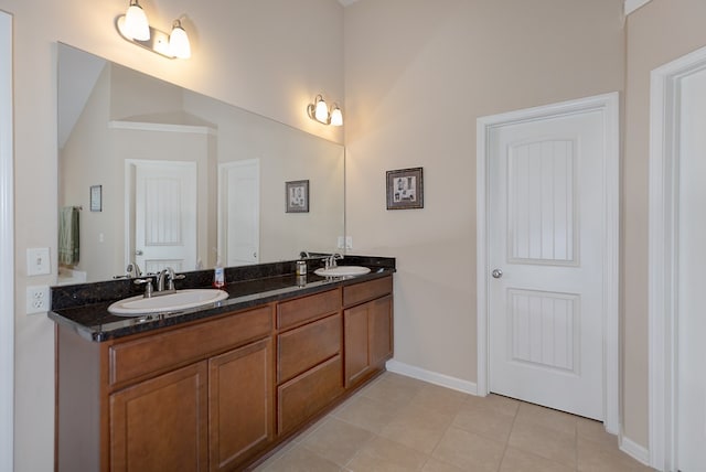 bathroom with tile patterned flooring, a sink, baseboards, and double vanity