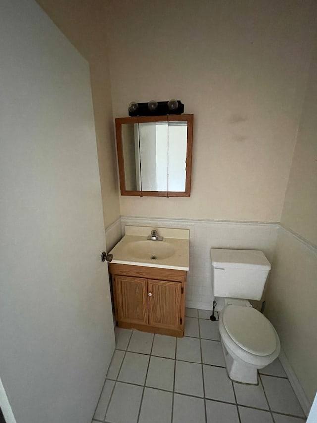 bathroom featuring tile patterned flooring, vanity, tile walls, and toilet