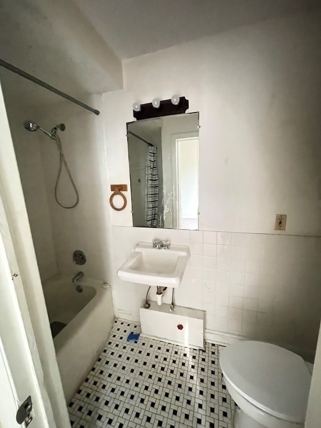 full bathroom featuring tiled shower / bath, toilet, sink, and tile walls