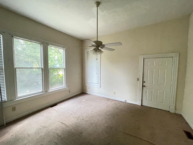 unfurnished dining area with ceiling fan, carpet, and a textured ceiling