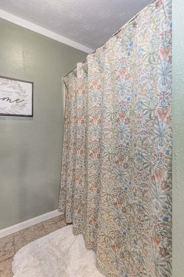 bathroom featuring tile patterned floors, baseboards, and a textured ceiling