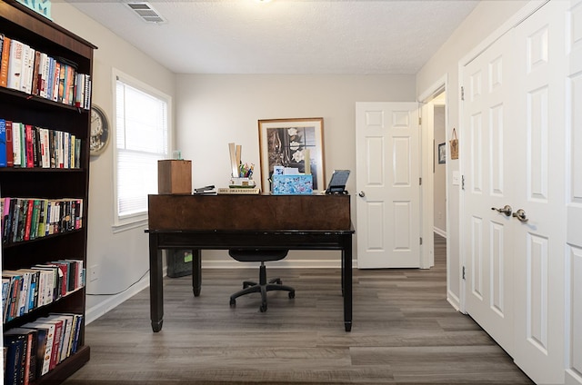 home office featuring visible vents, baseboards, a textured ceiling, and wood finished floors