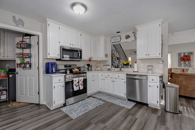 kitchen with light countertops, white cabinets, dark wood-type flooring, and stainless steel appliances