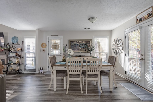 dining area featuring visible vents, dark wood-style flooring, and a wealth of natural light