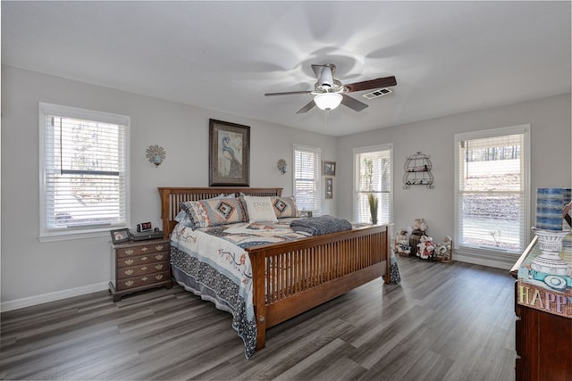 bedroom featuring visible vents, multiple windows, baseboards, and wood finished floors