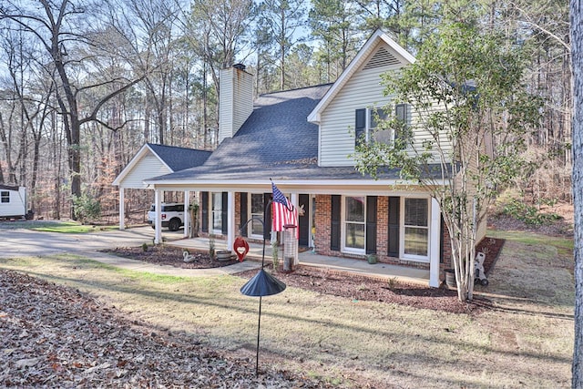 view of front of house with brick siding, covered porch, a shingled roof, an attached carport, and a chimney