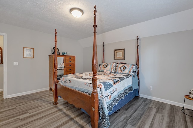 bedroom featuring baseboards, a textured ceiling, and wood finished floors