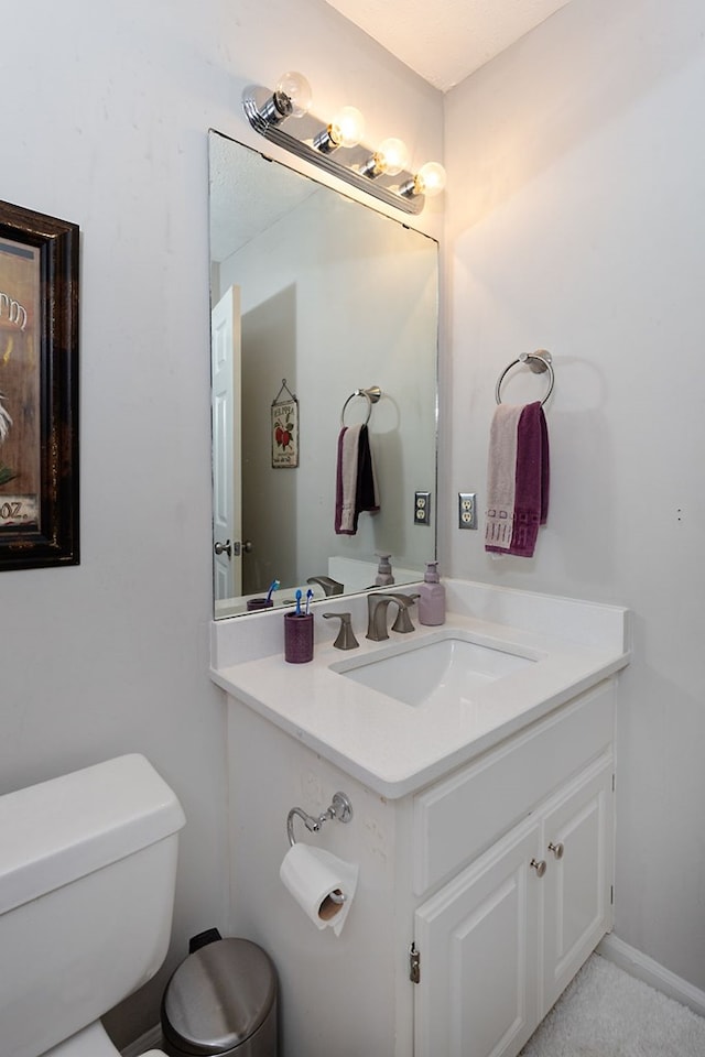 bathroom with baseboards, toilet, and vanity