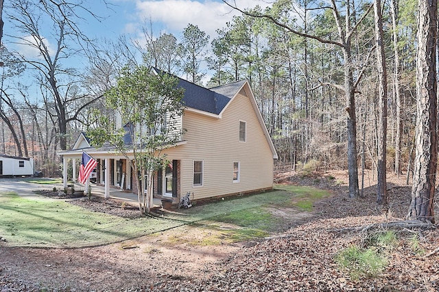 view of home's exterior with covered porch and a lawn