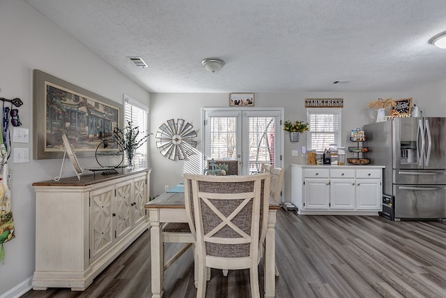 dining area with dark wood-style floors, visible vents, a textured ceiling, and baseboards