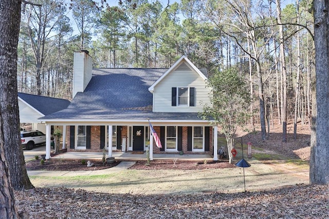 farmhouse with roof with shingles, an attached carport, a chimney, covered porch, and brick siding