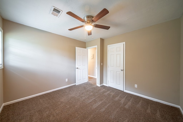 unfurnished bedroom with carpet, a textured ceiling, and ceiling fan