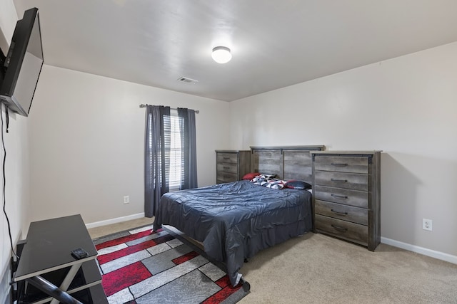 bedroom featuring visible vents, light colored carpet, and baseboards