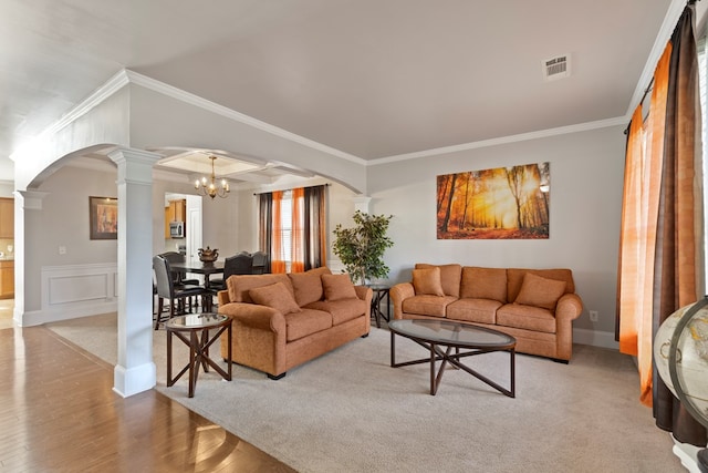 living area featuring visible vents, crown molding, a chandelier, decorative columns, and arched walkways