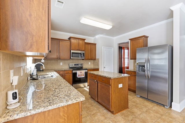 kitchen featuring visible vents, a center island, appliances with stainless steel finishes, brown cabinetry, and a sink