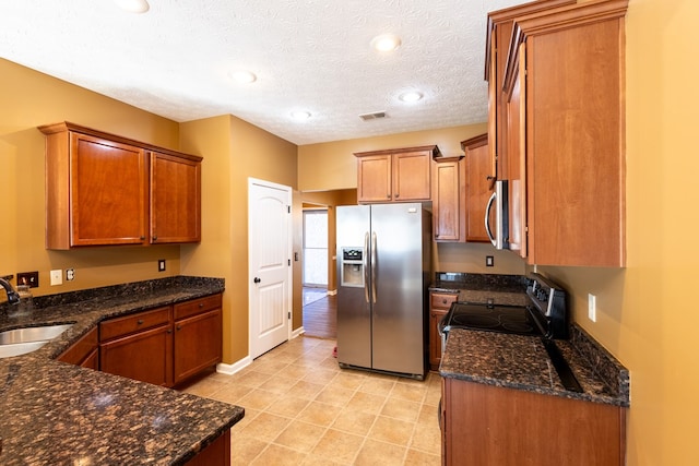 kitchen with appliances with stainless steel finishes, brown cabinetry, visible vents, and a sink