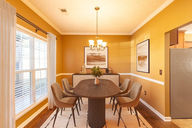 dining room featuring ornamental molding, visible vents, a notable chandelier, and wood finished floors