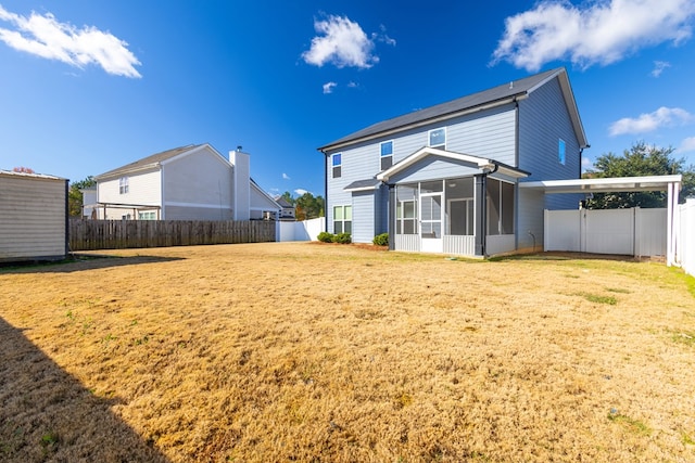 rear view of house featuring a lawn, a fenced backyard, and a sunroom