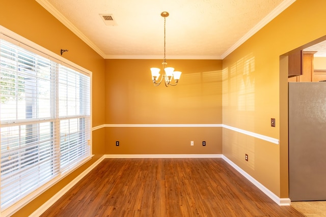 unfurnished dining area with a chandelier, wood finished floors, visible vents, baseboards, and crown molding