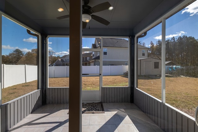 sunroom / solarium featuring ceiling fan and a residential view