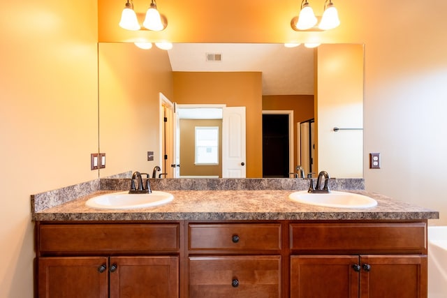 bathroom with visible vents, a sink, and double vanity