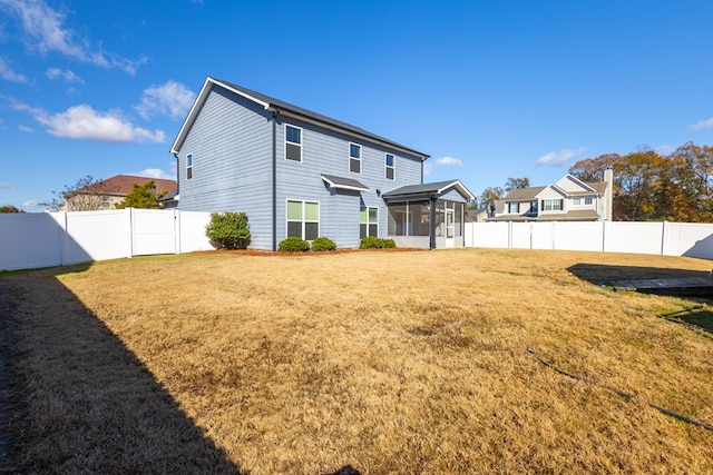 back of property with a sunroom, a fenced backyard, and a lawn