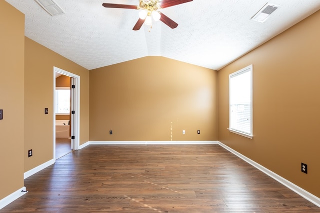 spare room featuring lofted ceiling, a textured ceiling, visible vents, and dark wood-style flooring